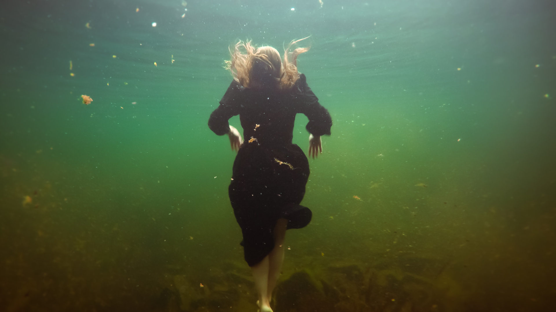 woman underwater in a black dress