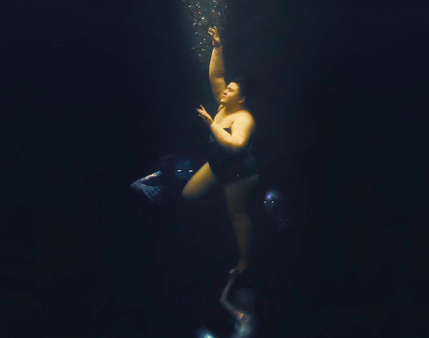a picture of a woman underwater being dragged down by mermaids