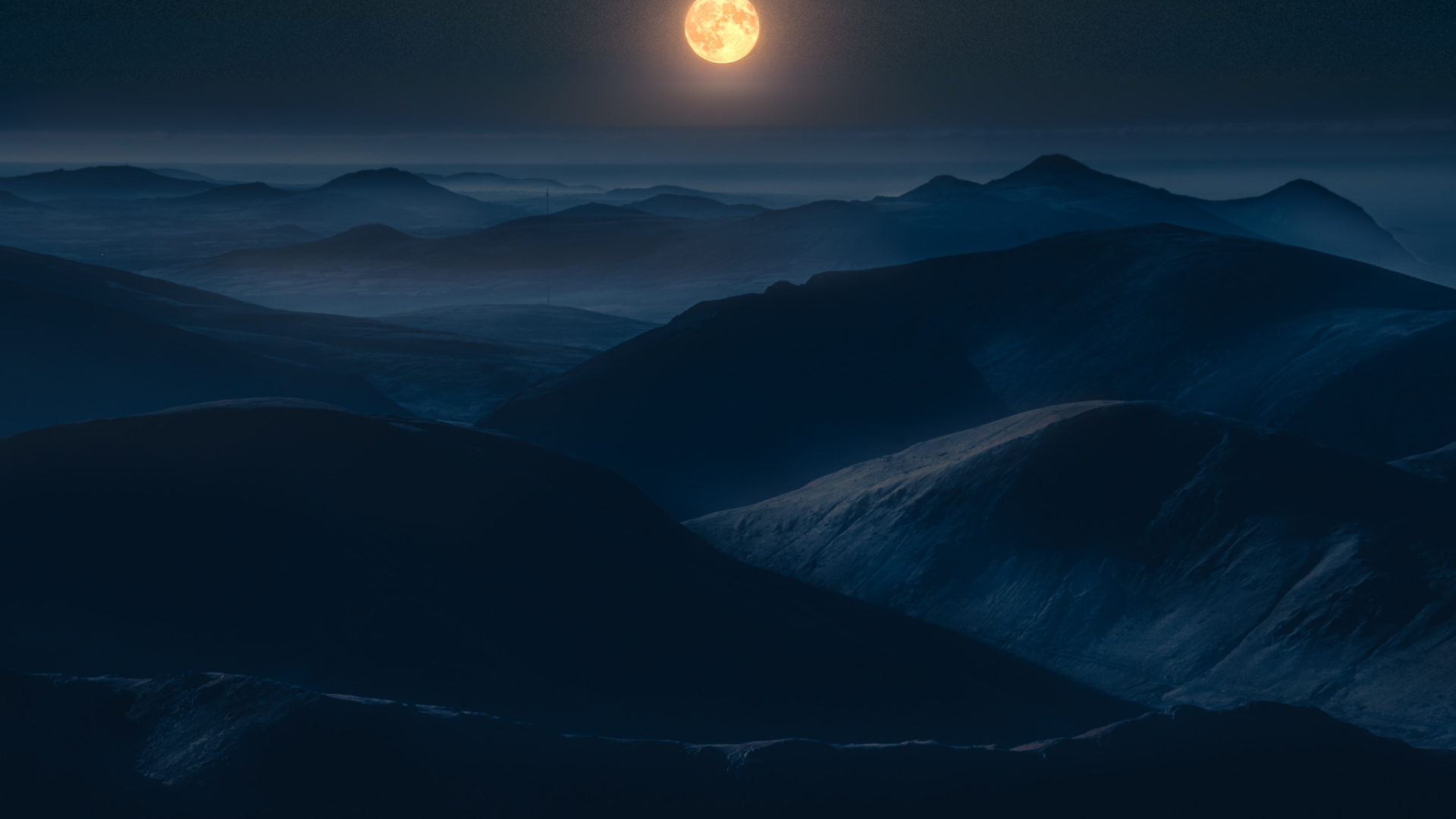 A large full moon above some mountains